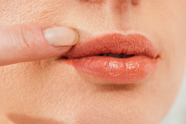 Ausgeschnittene Ansicht einer kranken Frau, die Herpes auf den Lippen berührt  - Foto, Bild