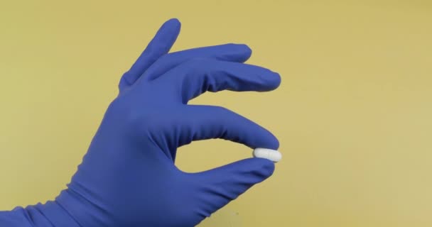 Een ovale witte pil in de hand gekleed in rubber steriele medische handschoen - Video