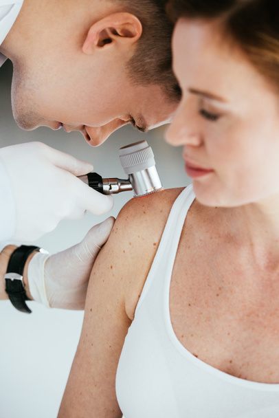 enfoque selectivo del dermatólogo que sostiene el dermatoscopio mientras examina al paciente con melanoma
  - Foto, Imagen