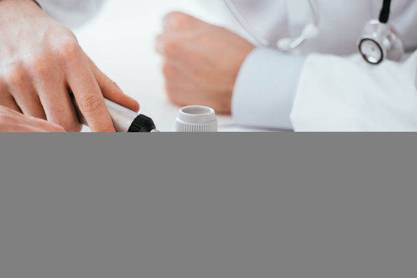 περικομμένη όψη του δερματολόγου που εξετάζει το χέρι της γυναίκας ενώ κατέχει δερματοσκόπιο στην κλινική  - Φωτογραφία, εικόνα