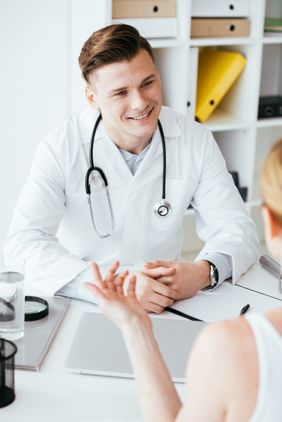 selective focus of happy doctor looking at patient in clinic  - Photo, Image