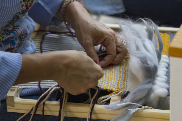Tejido en telar vertical manos trabajando lana azul y amarillo tejiendo tapiz con hilo de algodn - Foto, Imagen