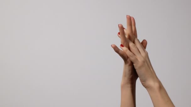 Krásné mladé ženské ruce s jasně červenou manikúru, jedna ruka jemně masírovala druhou, izolovaná na šedém pozadí - Záběry, video