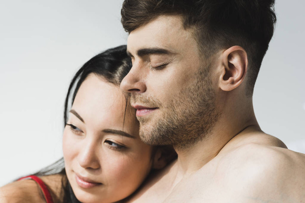atraente, pensivo asiático mulher perto bonito namorado com fechado olhos no cinza
 - Foto, Imagem