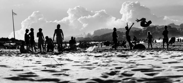 Силуэты людей на пляже, веселящихся во время отпуска
 - Фото, изображение