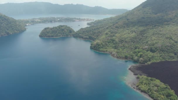 航空写真:バンダ諸島の活火山グヌンアピ溶岩の上を飛ぶマルクインドネシア緑豊かな緑の森ターコイズ水サンゴ礁の風光明媚な旅行先。ネイティブシネのようなD-logカラープロファイル - 映像、動画