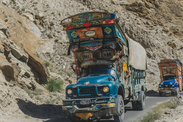 Gilgit Baltistan, Pakistan. 11 oktober 2015: Pakistaanse versierde vrachtwagens reizen op verharde weg, vervoer goederen via Karakoram Highway langs de berg. - Foto, afbeelding