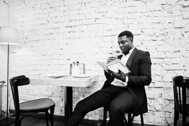 Strong powerful african american man in black suit sitting at ca - Foto, Imagen
