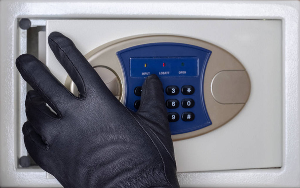 Siyah eldivenli bir hırsız güvenli kapıyı bir şifreyle açar. Evde, otelde ve ofiste güvenlik. Kavram. Değerli eşyaların ve paranın çalınması. - Fotoğraf, Görsel