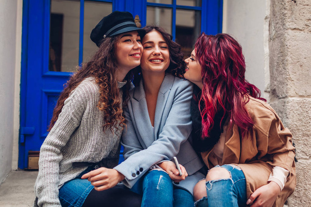 若い女性が街の通りで抱き合って笑っています。一緒に楽しい時間を過ごしている親友 - 写真・画像