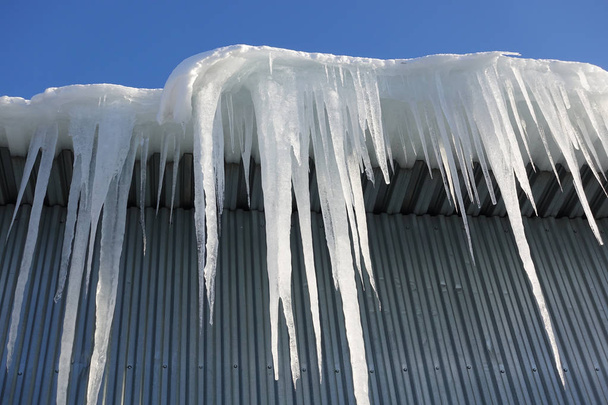 Pitkät, isot ja vaaralliset jääpuikot tiilitalon katolla - Valokuva, kuva
