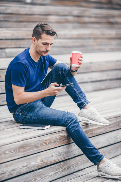 Ember az olvasó szöveges üzeneteket a mobiltelefon, míg séta a parkban - Fotó, kép