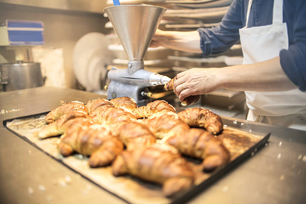 Pastry chef filling croissants with cream - Foto, Imagem