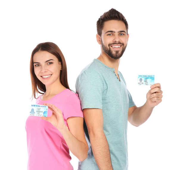 Happy young people with driving licenses on white background - Foto, afbeelding