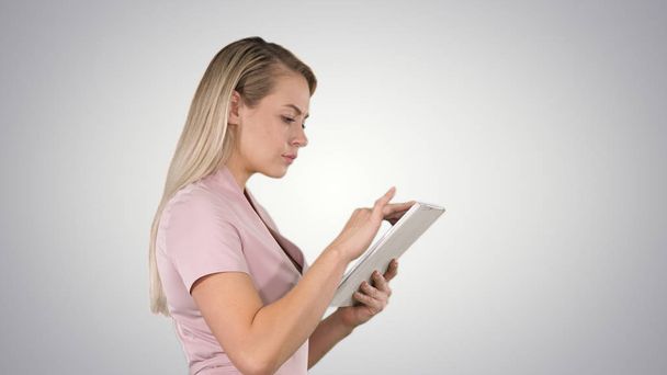 Girl holding digital tablet searching for something on gradient background. - Foto, Imagen