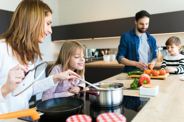 Beautiful cute family having fun while cooking together in the kitchen at home. - Photo, Image