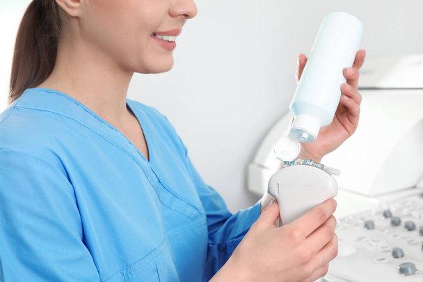 Sonographer covering ultrasound machine probe with gel in clinic, closeup - Fotoğraf, Görsel