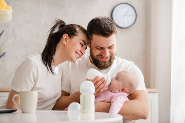 Happy young couple feeding infant from bottle - Foto, Imagen