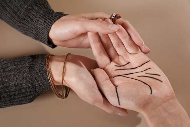 Chiromancer reading lines on woman's palm against color background, closeup - Foto, Imagem