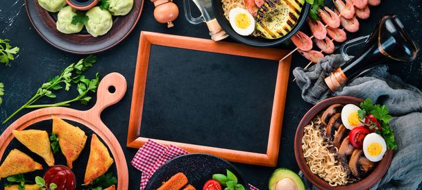 Set Asian food. Noodles, shrimp, Samsa, khinkali. On a black wooden background. Top view. Free copy space. - Фото, изображение