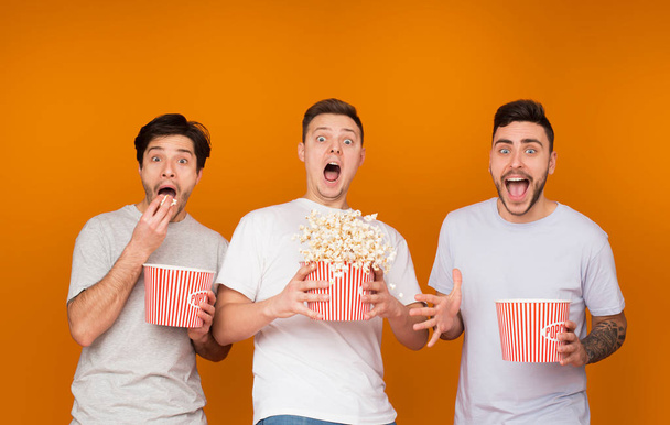 Geschokt mannen eten popcorn en enge film kijken - Foto, afbeelding