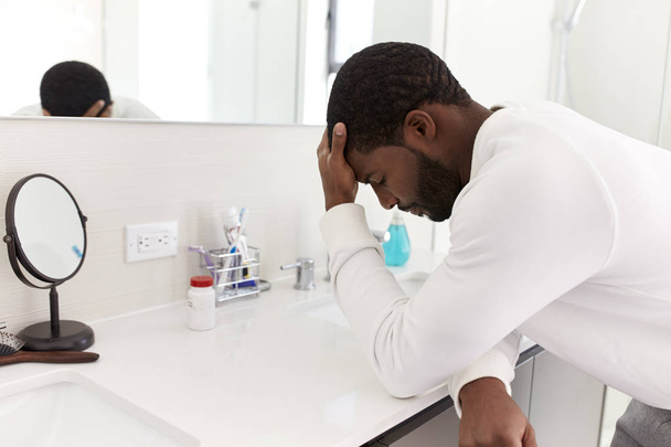 Depressed Man Leaning On Sink In Bathroom With Head In Hands - Фото, зображення