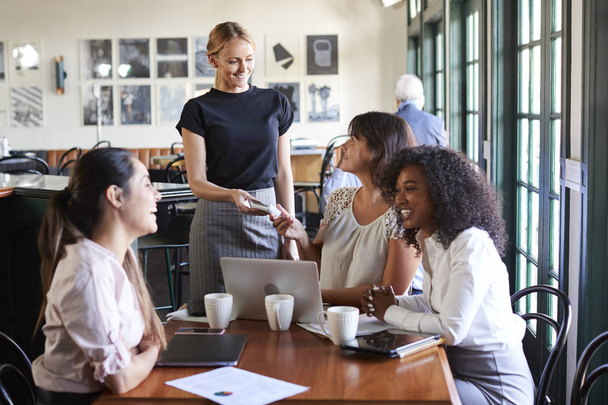 Businesswomen Paying Bill At Meeting Around Table In Coffee Shop - Foto, Imagen