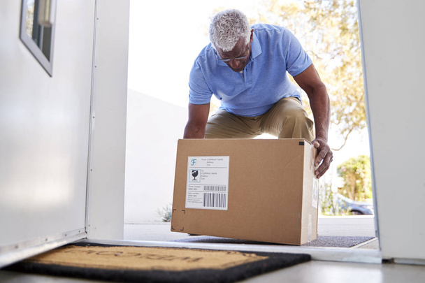 Senior Man Coming Back To Home Delivery In Cardboard Box Outside Front Door - Foto, imagen