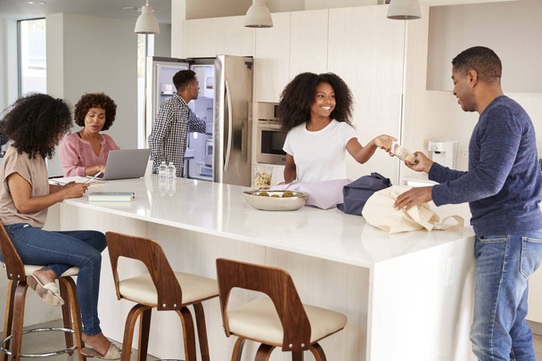 Black family unpacking groceries and spending time in their kitchen together - Фото, изображение