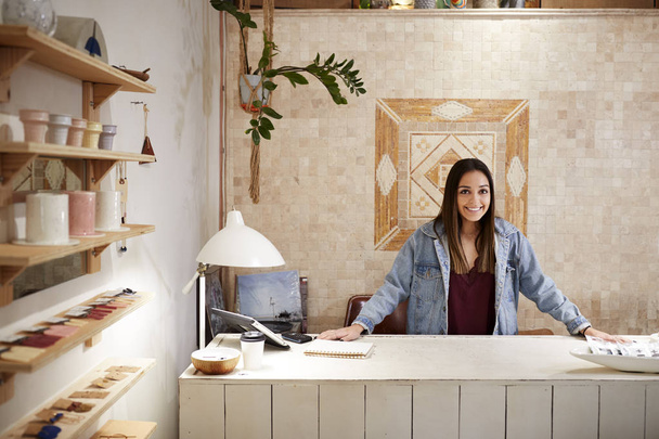 Portrait Of Female Owner Of Clothing And Gift Store Behind Sales Desk - Foto, imagen