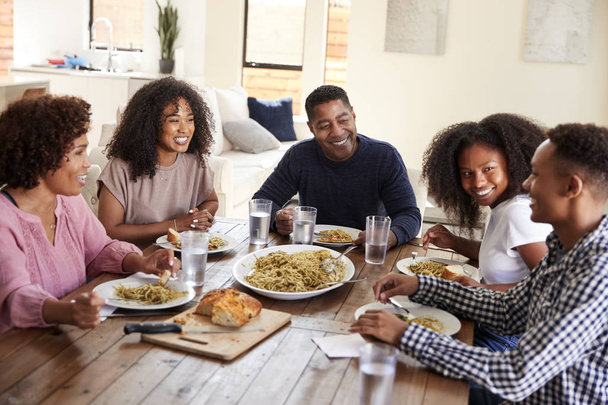 Middle aged black couple sitting at dinner table eating with their children - Φωτογραφία, εικόνα