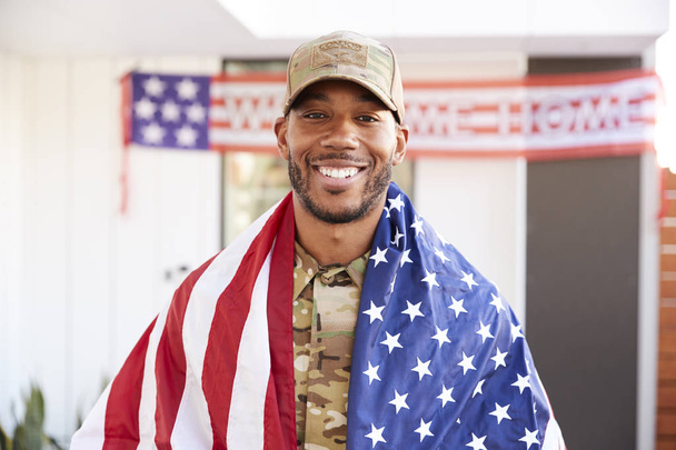 Millennial black soldier with US flag draped over his shoulders, smiling to camera, close up - Φωτογραφία, εικόνα
