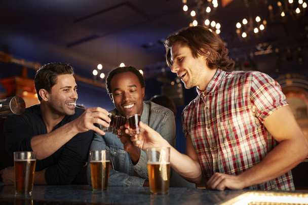 Group Of Male Friends Drinking Shots In Bar Together - Φωτογραφία, εικόνα