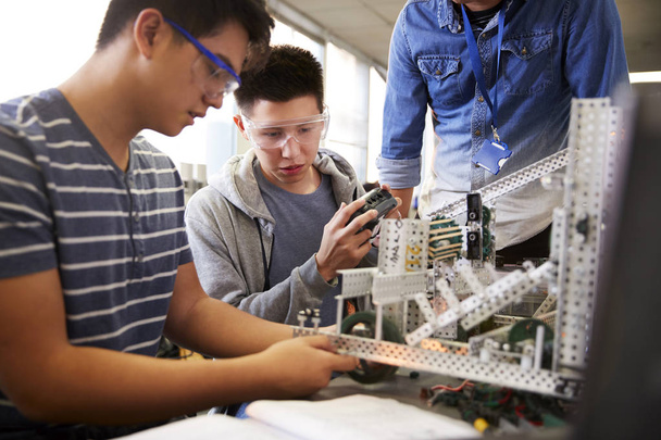 Teacher With Two Male College Students Building Machine In Science Robotics Or Engineering Class - Foto, imagen