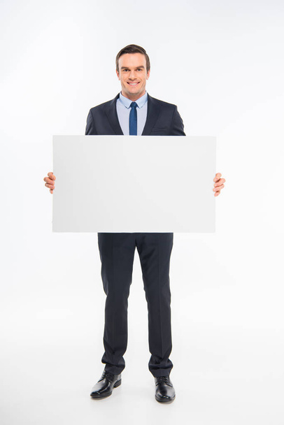 Smiling businessman holding blank card and looking at camera - Фото, изображение