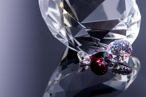 Diamante enorme e diversi cristalli chic su una superficie a specchio bianco, luccica e scintilla
 - Foto, immagini