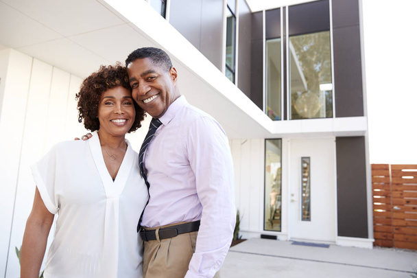 Middle aged black couple stand outside admiring their modern home, back view - Photo, Image