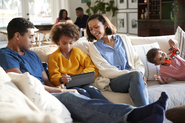 Three generation  family spending time at home in their living room, parents and kids in the foreground, grandparents in the background, selective focus - Foto, Imagen