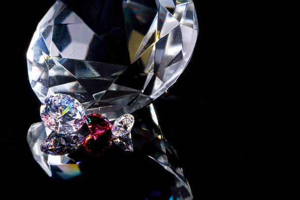 Diamant énorme et plusieurs cristaux chics sur une surface miroir noir profond, scintillement et éclat
 - Photo, image