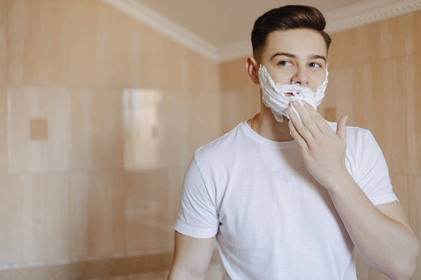 higiene de la mañana, el hombre se afeita con espuma
 - Foto, Imagen