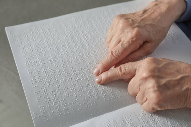 Blind senior person reading book written in Braille, closeup - Фото, изображение