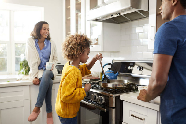 young family spending time together while preparing food in their kitchen - Foto, afbeelding