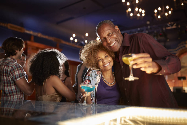 Portrait Of Senior Couple Drinking And Dancing In Bar Together - Foto, imagen