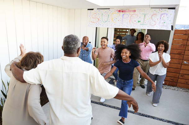 Black family running to welcome grandparents for a surprise family party - 写真・画像