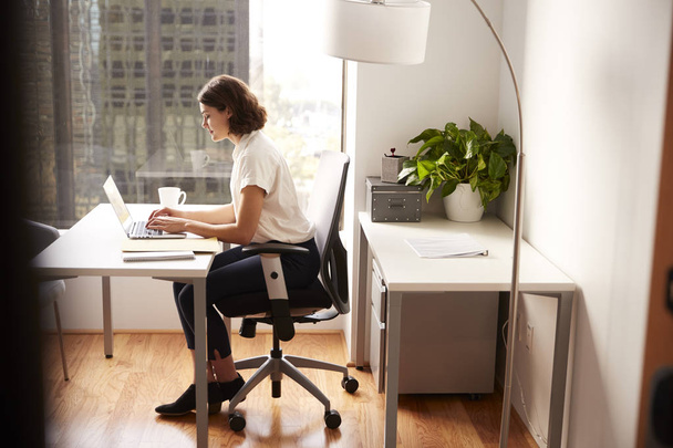 Businesswoman Sitting At Desk Working On Laptop In Modern Office - Valokuva, kuva