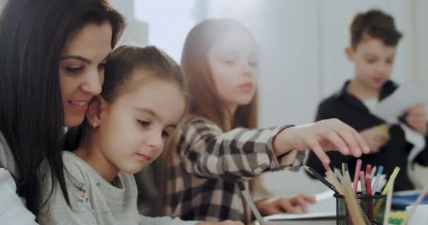 Крупним планом приваблива мати і її діти проводять цікавий час разом на столі, який вони малюють, і проводять ремесла в сонячний ранок
 - Кадри, відео