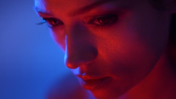 Közeli hajtás fantasztikus divat modell piros és kék neonfények órák alulról kamera feszülten. - Felvétel, videó