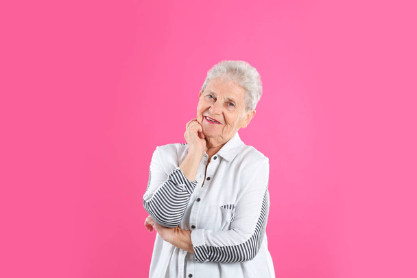 Portrait of grandmother in stylish clothes on color background - 写真・画像