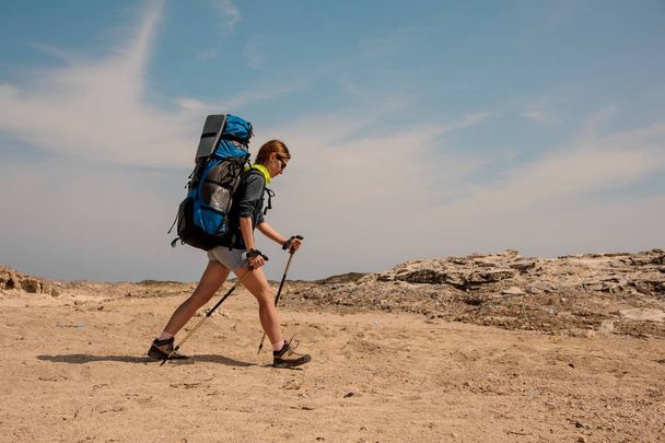 Young female hiker travelling with sticks in a desert - Foto, Imagem