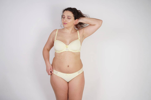 vrouwelijke vrouw met plus size lichaam in gele lingerie poseren op witte achtergrond in Studio - Foto, afbeelding